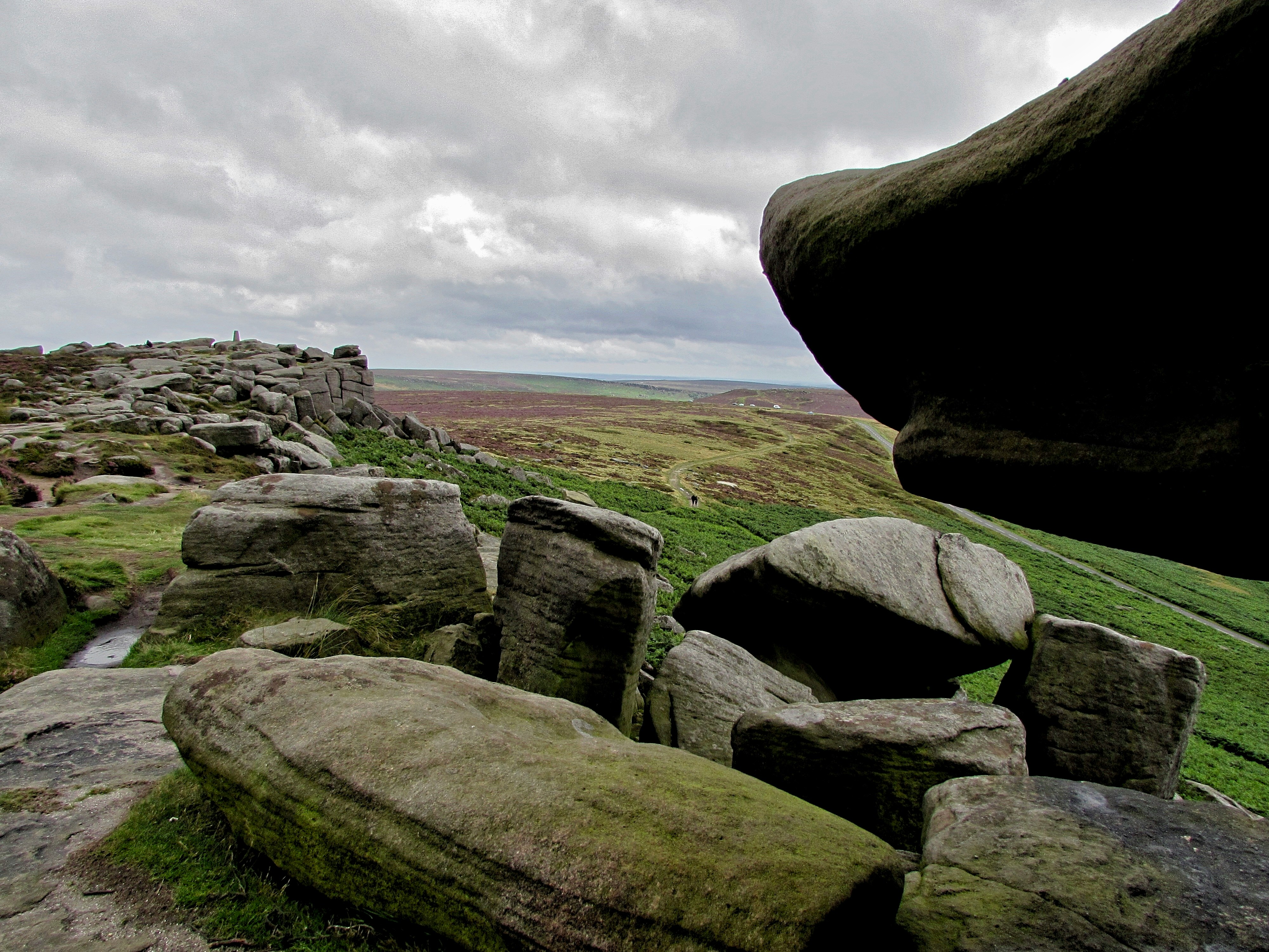 Dramatic rocky cliffs of Stanage Edge rising above the Peak District moors, with heather-covered slopes and expansive countryside views